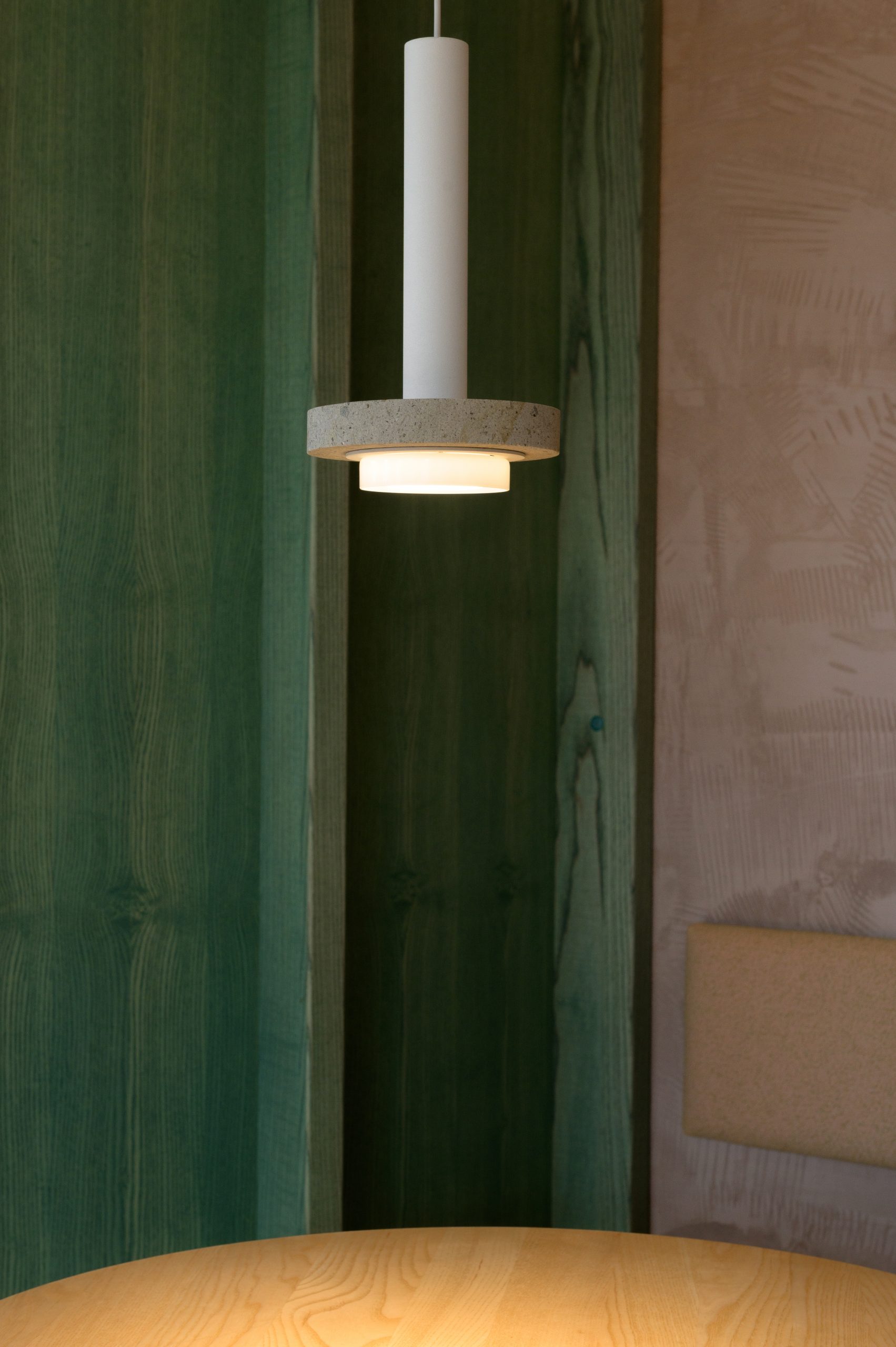 Pendelleuchte und im Hintergrund grünes Holz