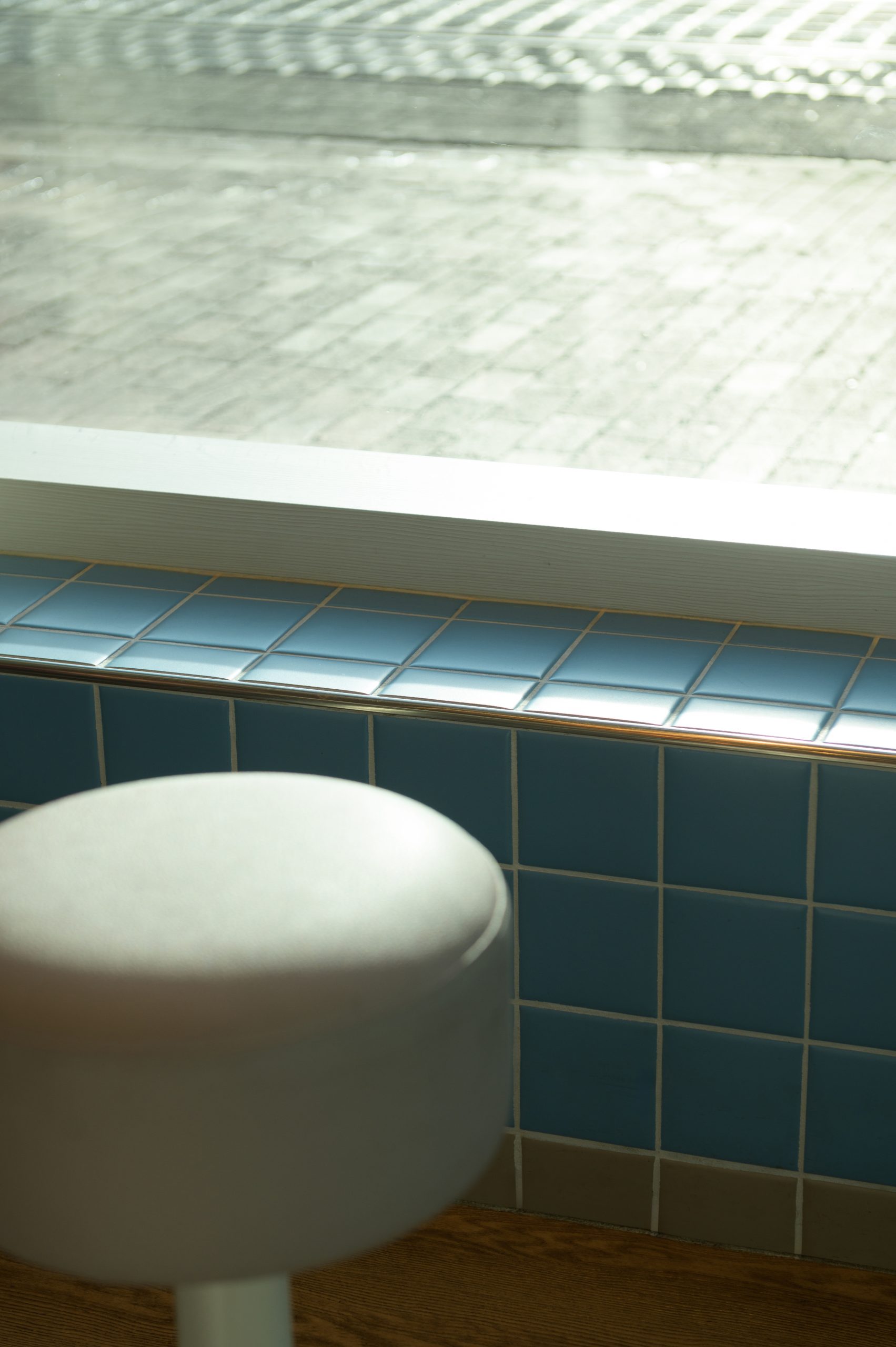 Detail Hocker mit farbigen Fliesen im Hintergrund